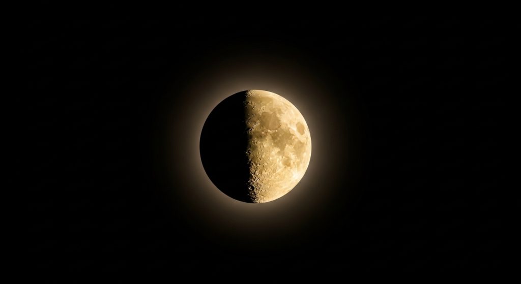 Best Aesthetic Moon Wallpapers for iPhone | Dark & Minimal Backgrounds 4 “Minimal black background with a glowing half-moon in the center designed for iPhone wallpaper.”