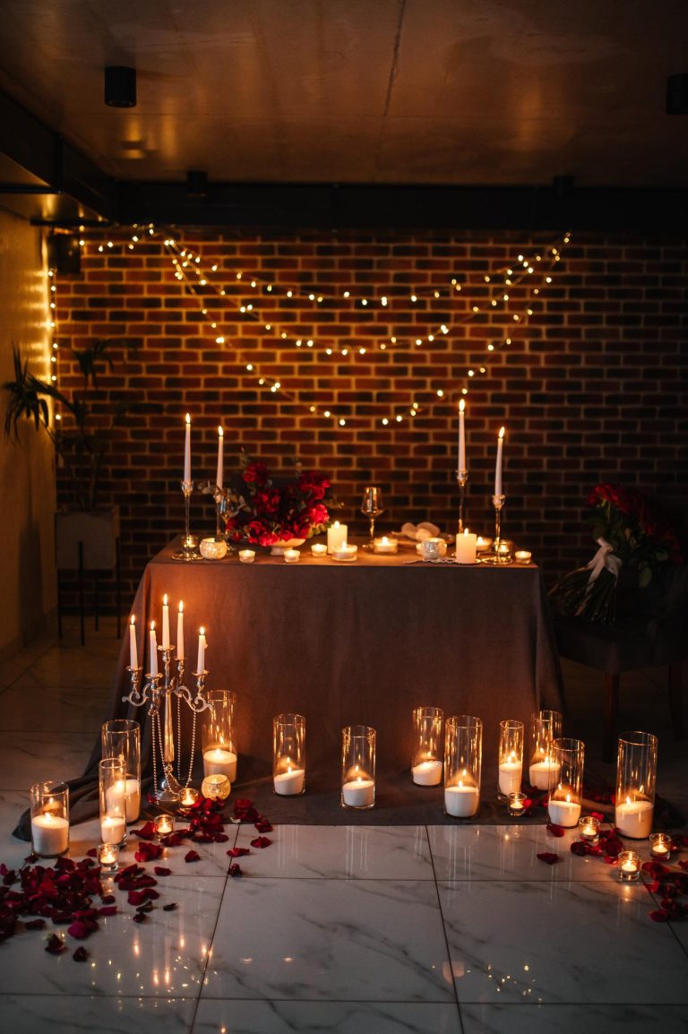 Elegant engagement party with neutral decor, candles, floral backdrop, and champagne tower
