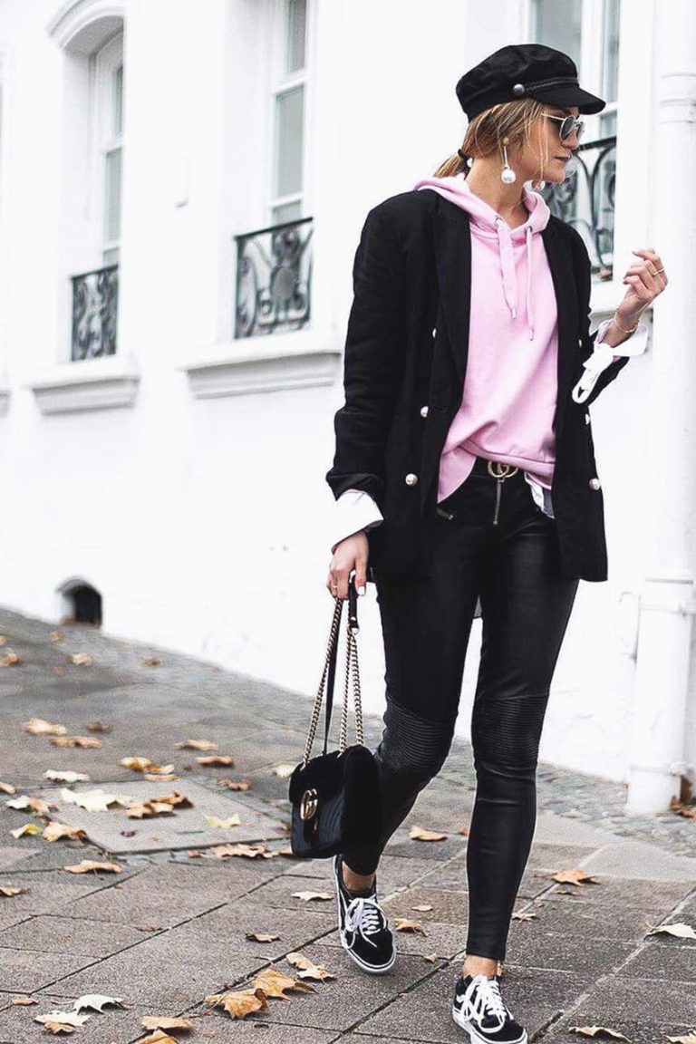 Woman layering oversized hoodie under structured blazer in stylish streetwear DSLR photography