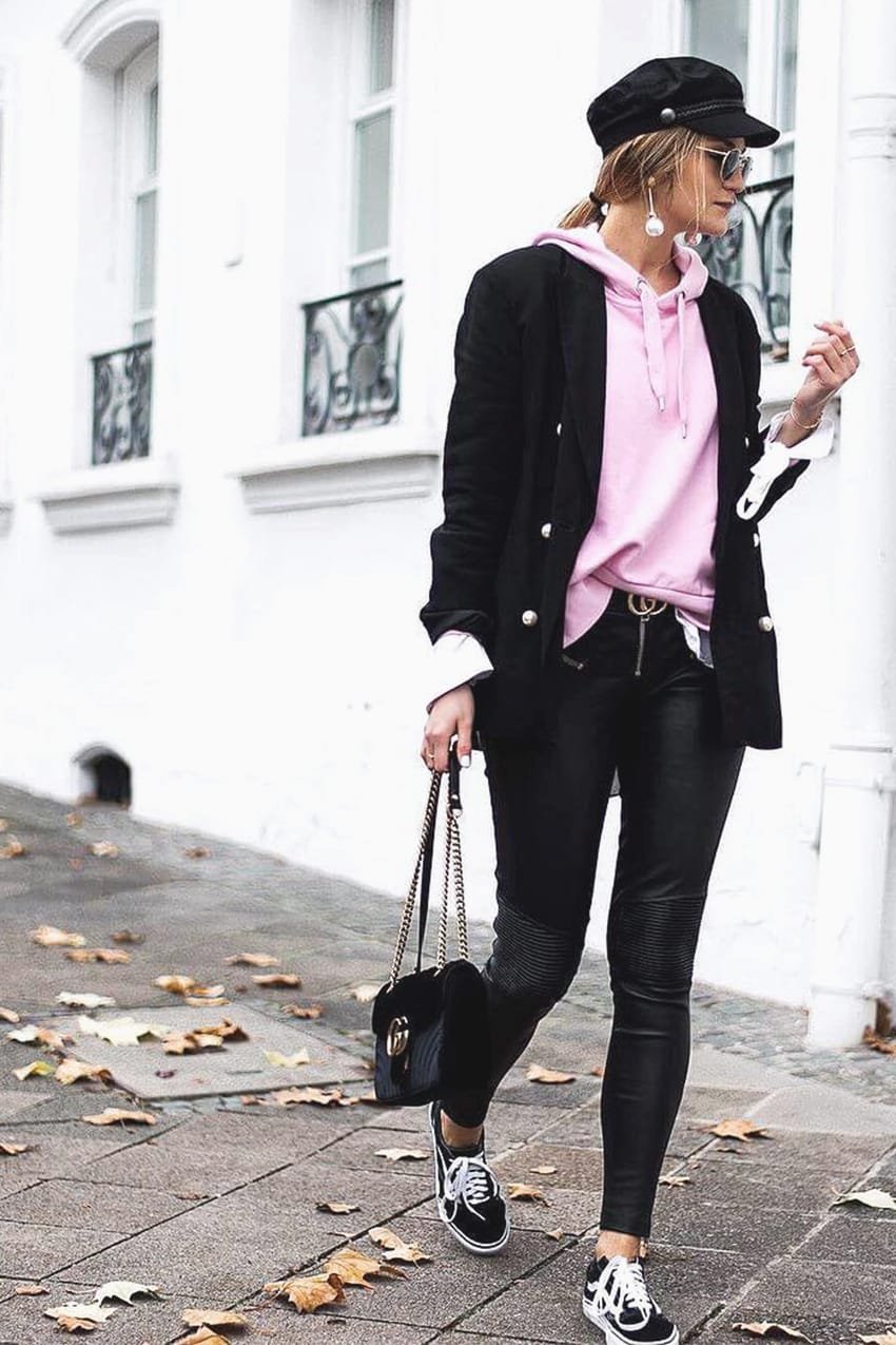 Woman layering oversized hoodie under structured blazer in stylish streetwear DSLR photography