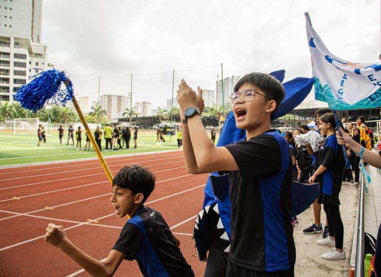 Students cheering during sports day race on school track field