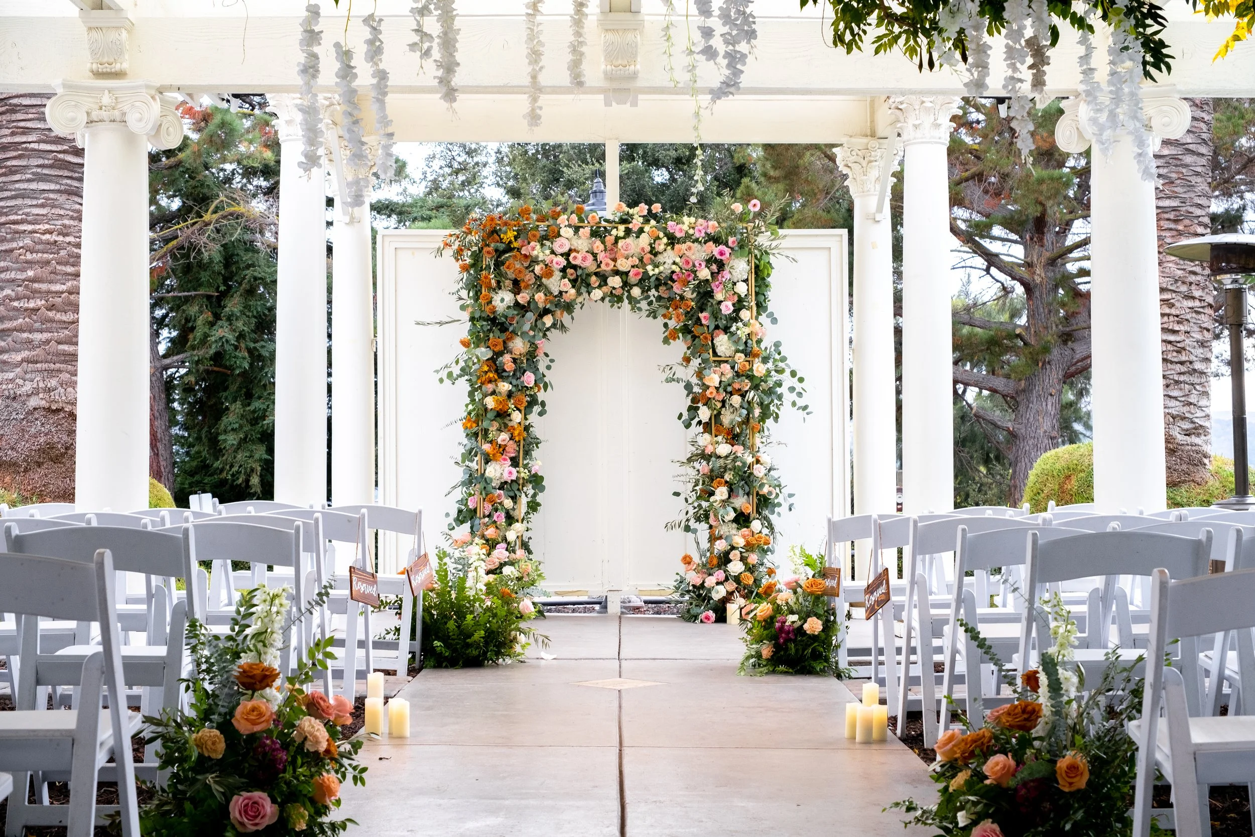 Elegant wedding aisle decoration with flowers, candles, and greenery creating a romantic ceremony setting.