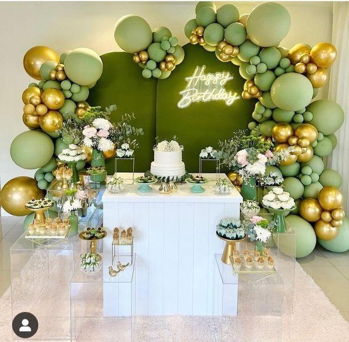A luxurious olive green birthday party setup featuring satin bows, elegant balloon arches, candlelit tables and gold accents styled in a sophisticated modern aesthetic for a chic bow themed celebration.