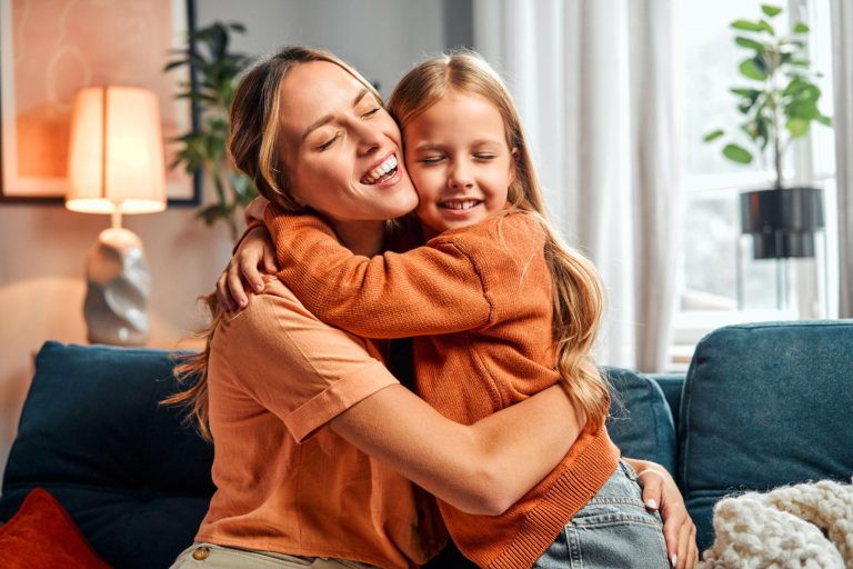 Smiling mother and daughter sharing a warm hug on a cozy sofa, capturing the emotional bond and endless love between a mother and child in a peaceful home setting