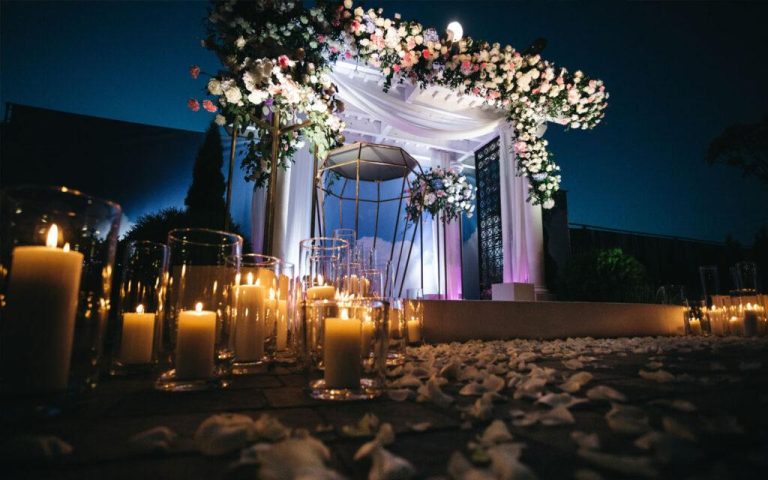 Elegant moody wedding reception featuring candlelight, dark florals, rich textures, and romantic décor.
