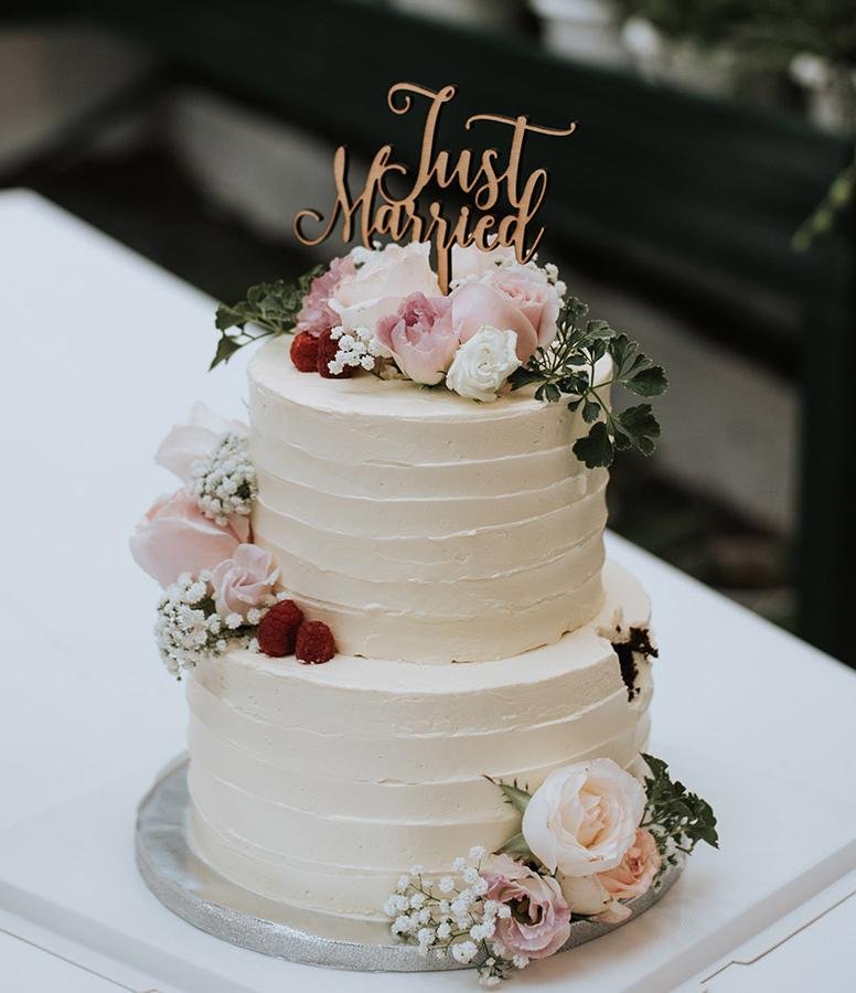 Luxury white wedding cake with elegant Just Married topper, romantic roses, candlelit reception