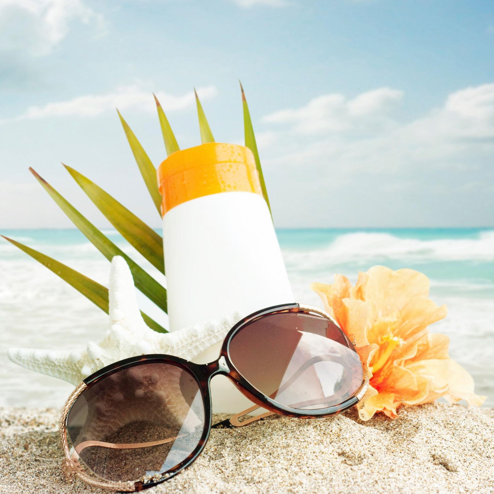 Premium sunscreen bottles displayed on a sunny beach with summer accessories.